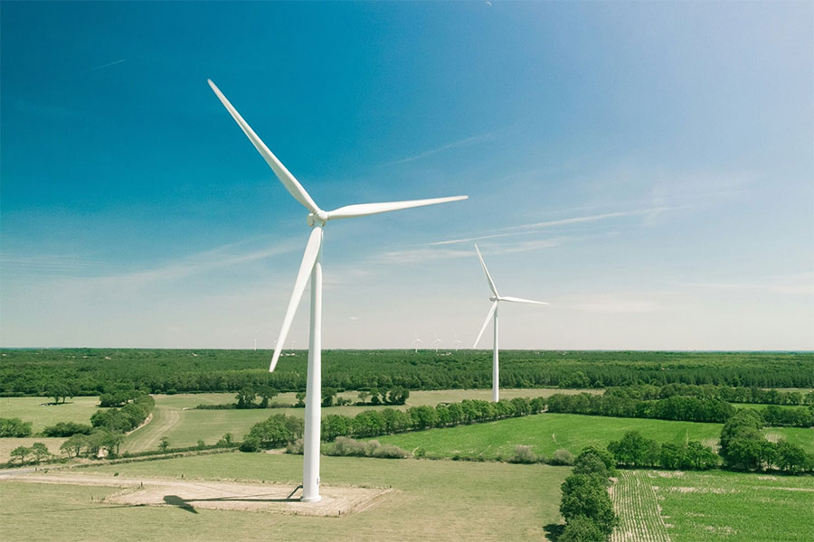 A modern wind turbine set against a clear blue sky, with its blades in mid-rotation, epitomizing sustainable energy solutions.